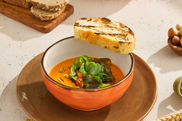 Delicious Pumpkin Cream Soup with Fresh Herb Mix and Toast in Rustic Setting
