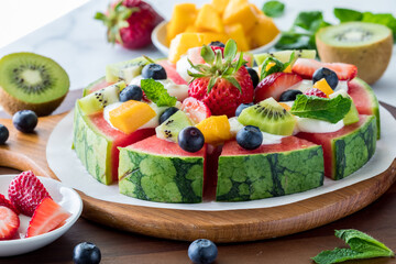 A close up of a watermelon pizza topped with cream cheese and fresh fruit.
