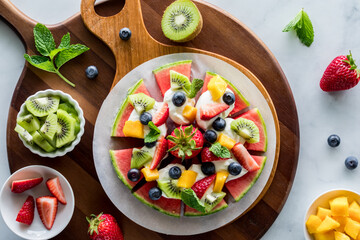 A juicy watermelon pizza topped with fresh fruit pieces, ready for sharing.