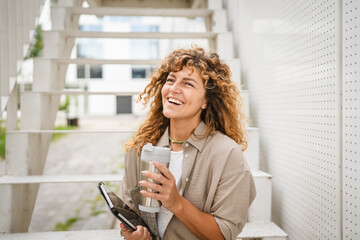 Portrait of beautiful adult woman sit and hold tablet and thermos cup