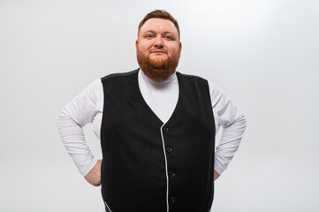 Hey you! Portrait of a happy, emotional bearded man in a light t-shirt and a black vest on a light background. Studio shot.