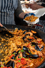 Street food in London, food court on Portobello road Saturday market, fresh prepared colorful paella with rice and sea food big pan, ready to eat