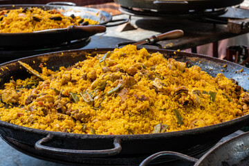Street food in London, food court on Portobello road Saturday market, fresh prepared colorful paella with rice and sea food big pan, ready to eat