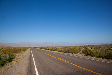 A straight road goes into the horizon at the Chisos Mountains at Big Bend National Park in Texas