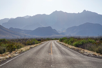 A straight road goes into the horizon at the Chisos Mountains at Big Bend National Park in Texas