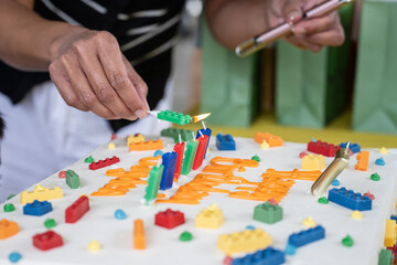 Female hands begin to light the colorful candles of the birthday cake during the party