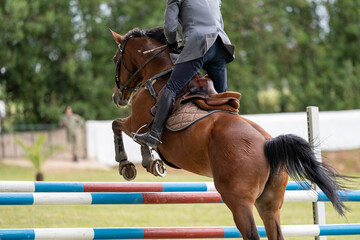 a rider in military uniform on a horse flies over an obstacle