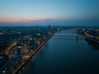 Naklejka premium The skyline of Cologne, Germany just after sunset. Inland cruise ship on the river rhine passing.