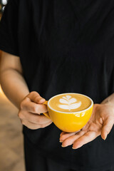 Barista holding a cup of cappuccino coffee in the hands