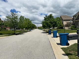 Blue trash cans line the street on trash day in an Indiana Neighborhood with copy space.