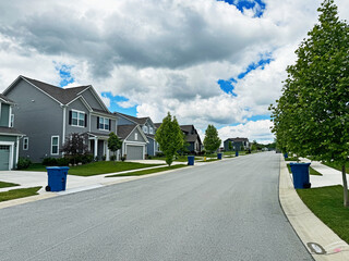 Blue trash cans line the street on trash day in an Indiana Neighborhood with copy space.