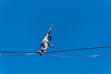 un funambule dans la nature. Funambule en extérieur naturel. Acrobate sur un fil en hauteur. Funambule sur une corde tendue. Funambulisme dehors.. Equilibre © david