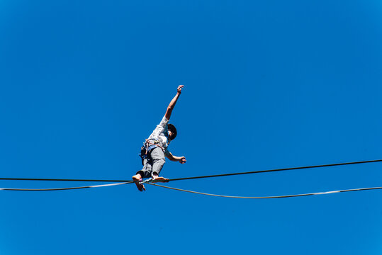 un funambule dans la nature. Funambule en extérieur naturel. Acrobate sur un fil en hauteur. Funambule sur une corde tendue. Funambulisme dehors.. Equilibre - Powered by Adobe