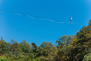 un funambule dans la nature. Funambule en extérieur naturel. Acrobate sur un fil en hauteur. Funambule sur une corde tendue. Funambulisme dehors.. Equilibre © david