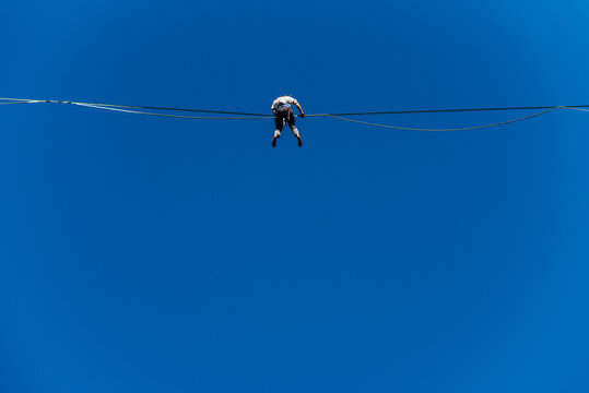 un funambule dans la nature. Funambule en extérieur naturel. Acrobate sur un fil en hauteur. Funambule sur une corde tendue. Funambulisme dehors.. Equilibre