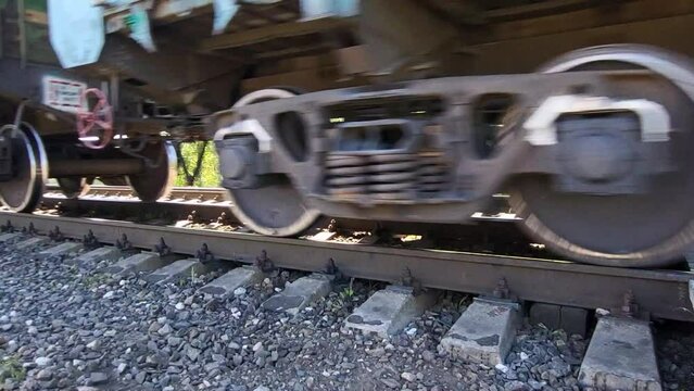 The wheels of an old train on the railway tracks run past the camera