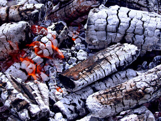 Smoldering embers of fire bbq background. Black charcoal & red fire flame texture. Firewood burning embers in stove - concept of fire wood heating. Charcoal bbq fireplace with gloving smouldering wood