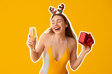 Happy young woman in swimsuit holding gift box and glass of champagne on yellow background....