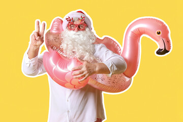 Santa Claus with swim ring showing victory gesture on yellow background. Christmas in July