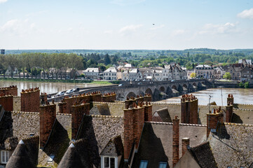 View.on old part of town of Gien on the Loire river, in Loiret department, France, houses with tiled roofs and chimneys, river and bridge
