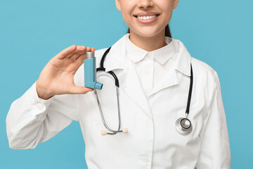 Portrait of female doctor with inhaler on blue background