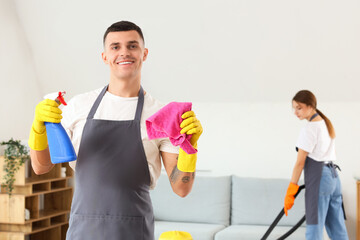 Male janitor with rag and detergent in room