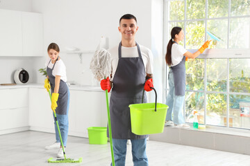 Male janitor with mop and bucket in kitchen