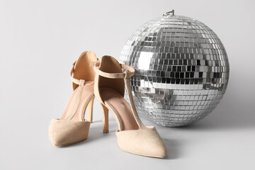 Pair of stylish female shoes and disco ball on white background