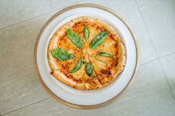 Color photo of gourmet margherita pizza with fresh basil leaves on top of it