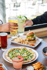 Two people are raising their glasses to toast, while a table full of food  is in the background. Color vertical image