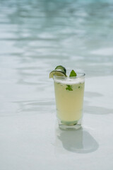 Mint mojito cocktail with pool water in background. Close up color vertical photo 