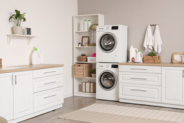 Interior of modern laundry room with washing machines and cleaning supplies