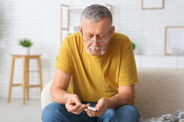 Senior man checking blood sugar level at home. Diabetes concept