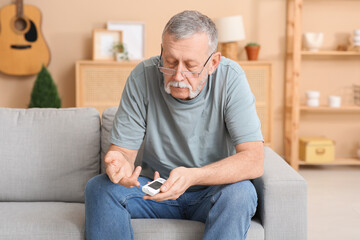 Senior man checking blood sugar level at home. Diabetes concept