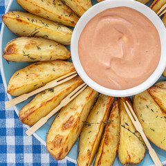 Potato chips laid out in the form of flower. Oven baked potato served with rose sauce. Top view.