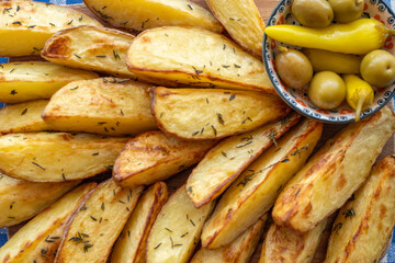 Oven baked potato wedges served with pickled peppers and olives.