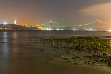 Night view of illuminated bridge over calm waters in Lisbon, Portugal