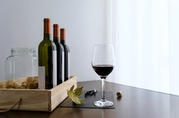 Copa de vino tinto malbec sobre impecable mesa de madera con botellas de vino al costado, corcho y...