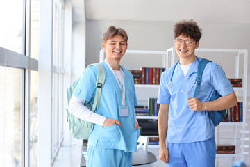 Male medical interns with backpacks near window in library