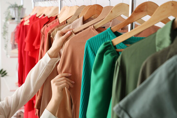 Female hands choosing dress in wardrobe
