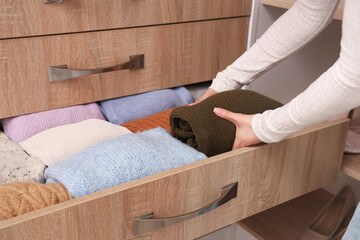 Woman taking sweater from chest of drawers at home