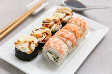 Plate with tasty sushi rolls on light background, closeup