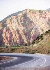 Mountain road made of asphalt serpentine meanders among mountain slopes in Tajikistan in the mountains, Pamir Highway in the evening in the mountains