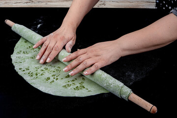 Green Pasta with Spinach. Pasta with spinach. Female chef rolls out green spinach pasta dough with...