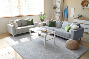Interior of living room with cozy sofa, table and surfboard