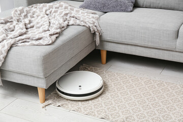Modern robot vacuum cleaner under sofa at home