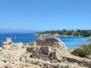 Photo of the Temple of Apollo ruins on Aegina Island, Greece, with Kolona Beach and its crystal-clear waters in the background, offering a stunning blend of ancient history and scenic beauty.