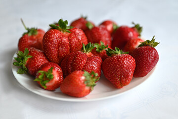 Truskawki na talrzu, na białym obrusie.