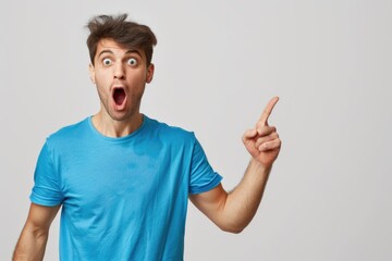 Fototapeta premium Shocked Guy. Young Man in Blue T-shirt Pointing with Amazement, WOW Expression