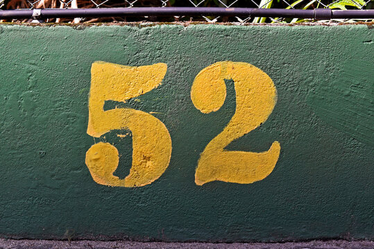 Number 52 painted in yellow on a green wall